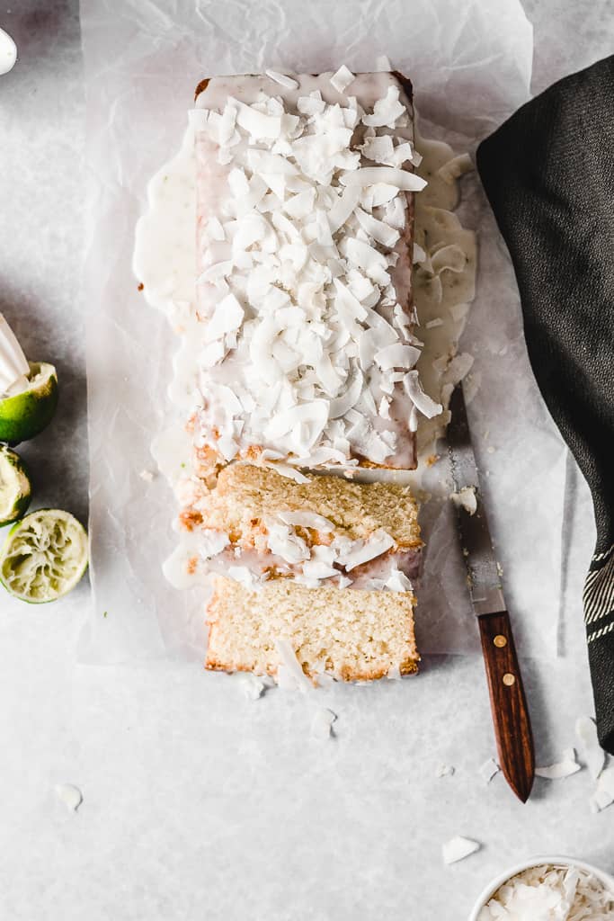 Top down view of coconut lime cake covered in coconut flakes, with two pieces sliced.