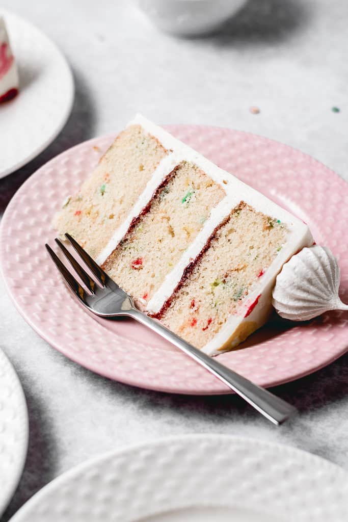 This Funfetti layer cake is perfect for birthdays, celebrations or just because! Soft and moist vanilla funfetti cake layers, paired with silky vanilla buttercream and filled with homemade strawberry jam. Learn how to make it from scratch, it's easy!  www.anasbakingchronicles.com