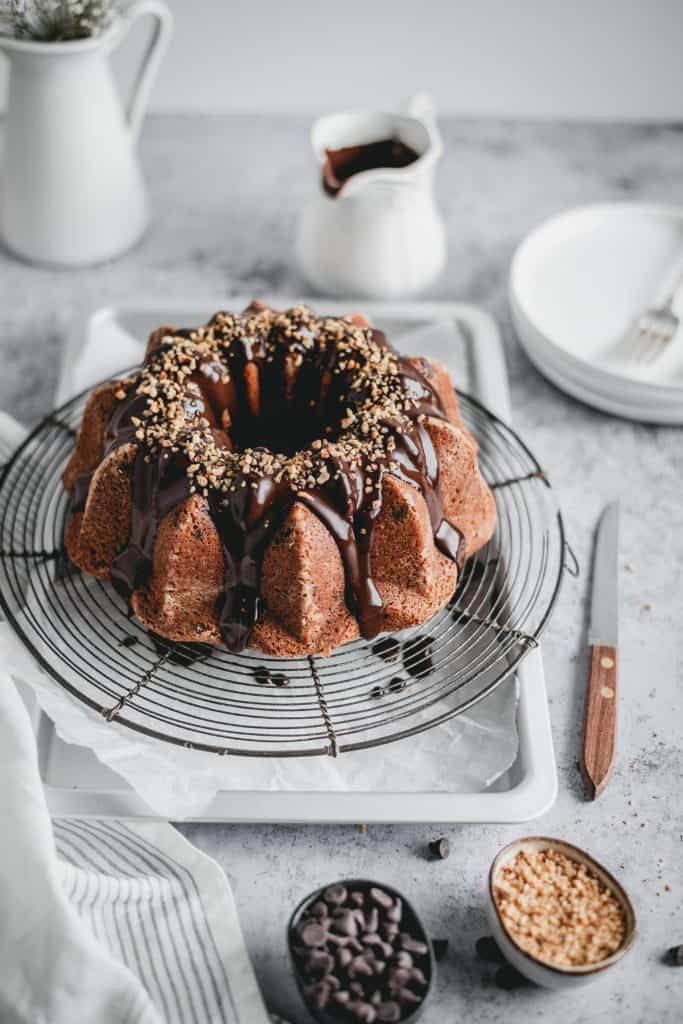 Moist chocolate chip banana cake with a hint of cinnamon, topped with delicious dark chocolate ganache and hazelnut crunch. Perfect treat for a Sunday afternoon!⎪www.anasbakingchronicles.com