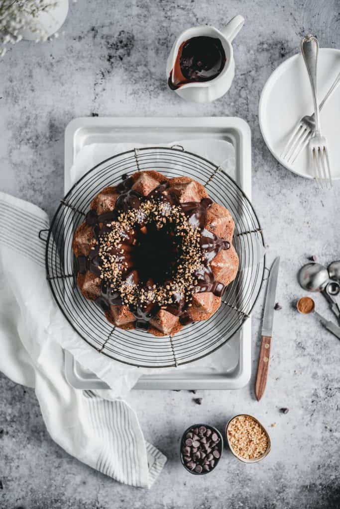 Moist chocolate chip banana cake with a hint of cinnamon, topped with delicious dark chocolate ganache and hazelnut crunch. Perfect treat for a Sunday afternoon!⎪www.anasbakingchronicles.com