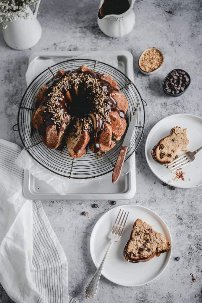 Moist chocolate chip banana cake with a hint of cinnamon, topped with delicious dark chocolate ganache and hazelnut crunch. Perfect treat for a Sunday afternoon!⎪www.anasbakingchronicles.com