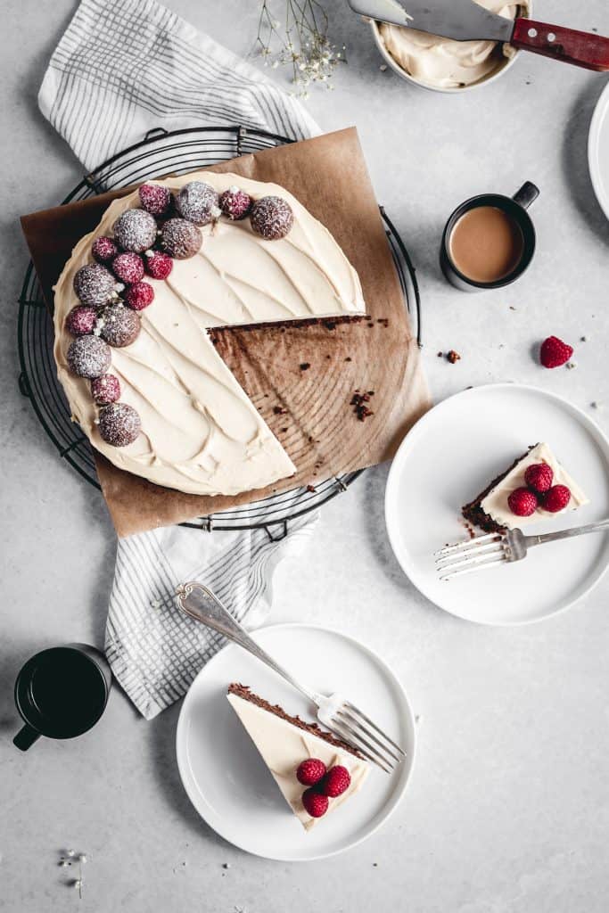 Cut slices of flourless and gluten free chocolate cake with Irish cream mascarpone frosting, decorated with raspberries.