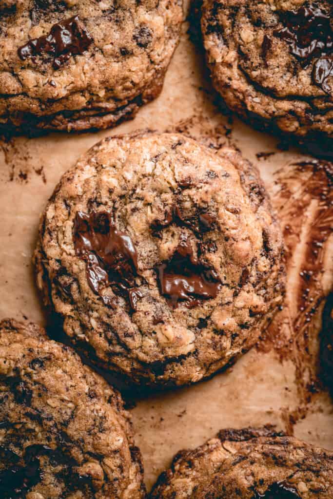 A close up baked oatmeal chocolate chip cookie with melty pool of chocolate.