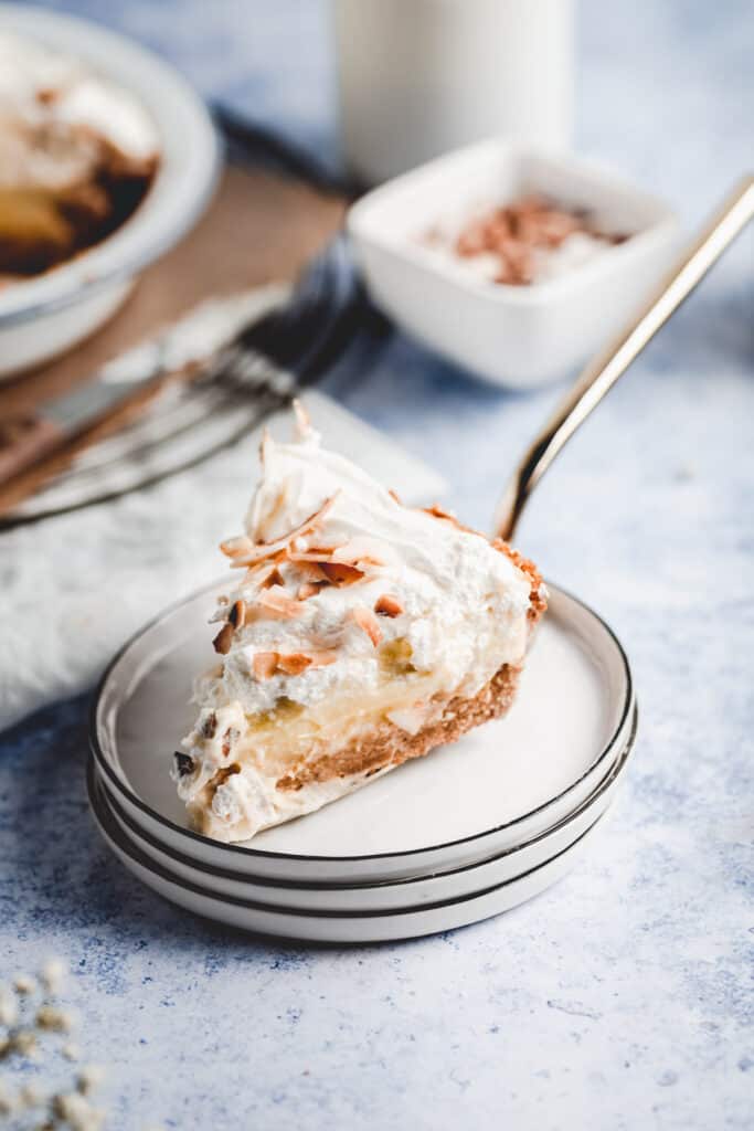 A creamy slice of coconut cream pie, served on three plates.