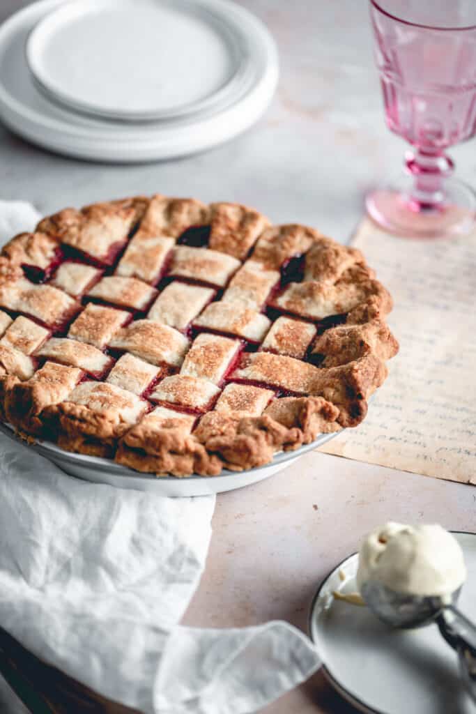 Homemade Cherry Pie with a scoop of ice cream aside, some glasses and plates.