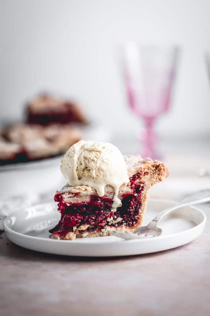 A piece of homemade cherry pie with ice cream on top.