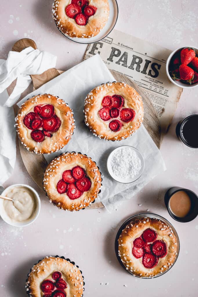 Brioche tarts made with tonka bean pastry cream and strawberries. Served on a wooden tray, with coffee mugs.