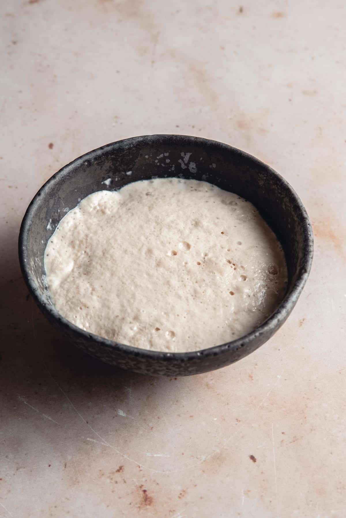 A bowl with frothy mix of yeast and milk.