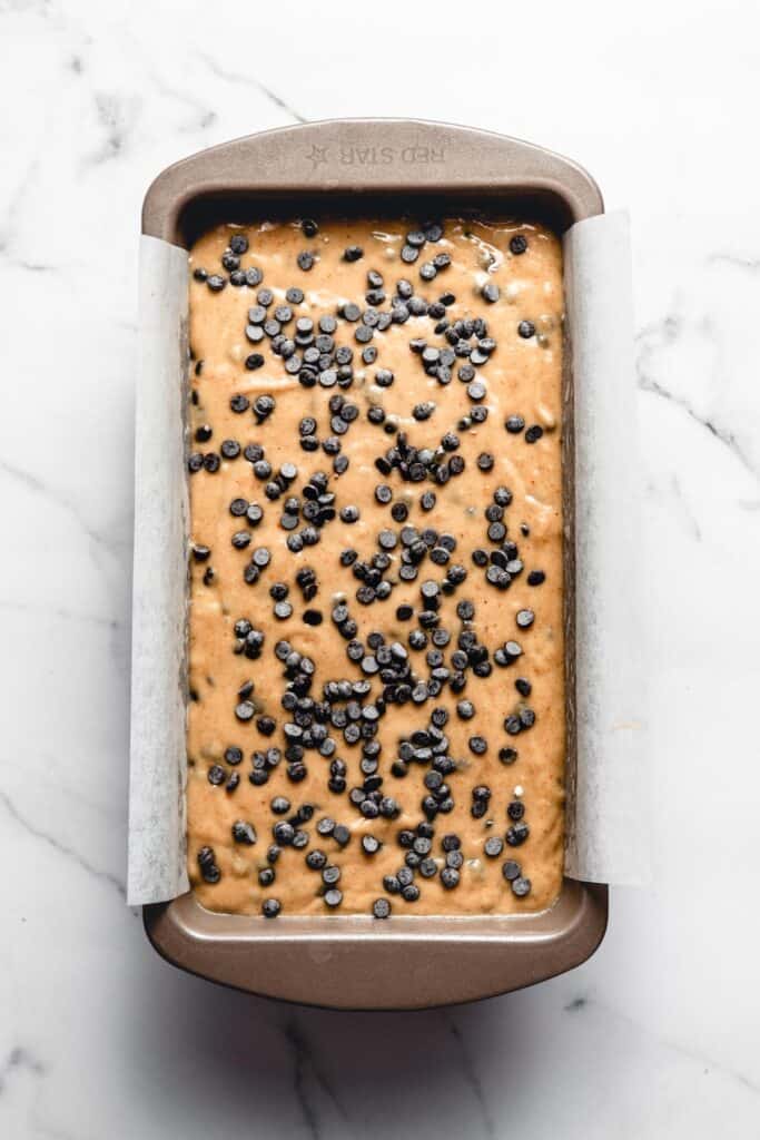 Step 5. Banana bread in a loaf pan with chocolate chips on top, before baking.