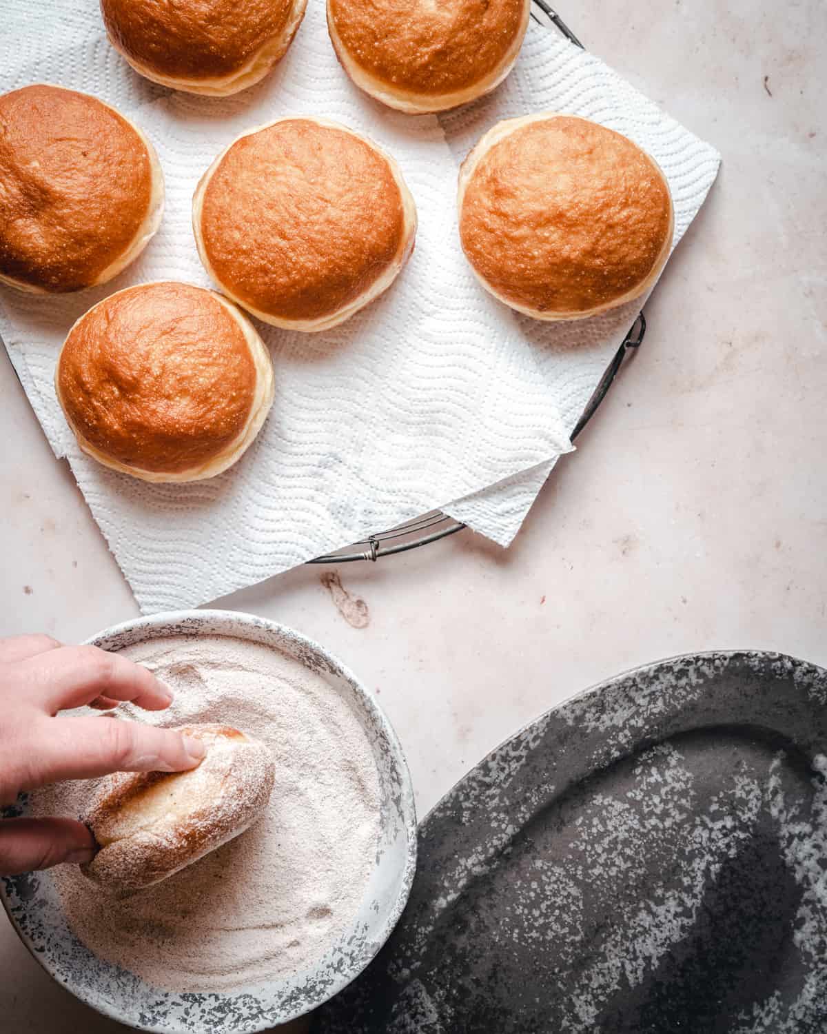 Coating fried doughnuts in cinnamon sugar