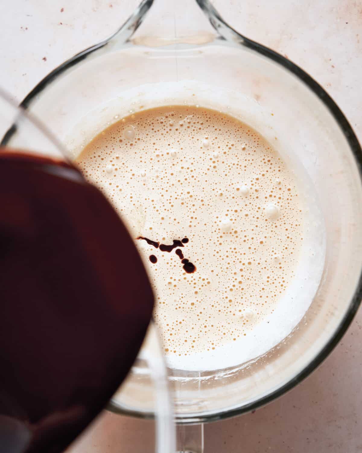 Melted chocolate being poured into the egg and sugar mixture.