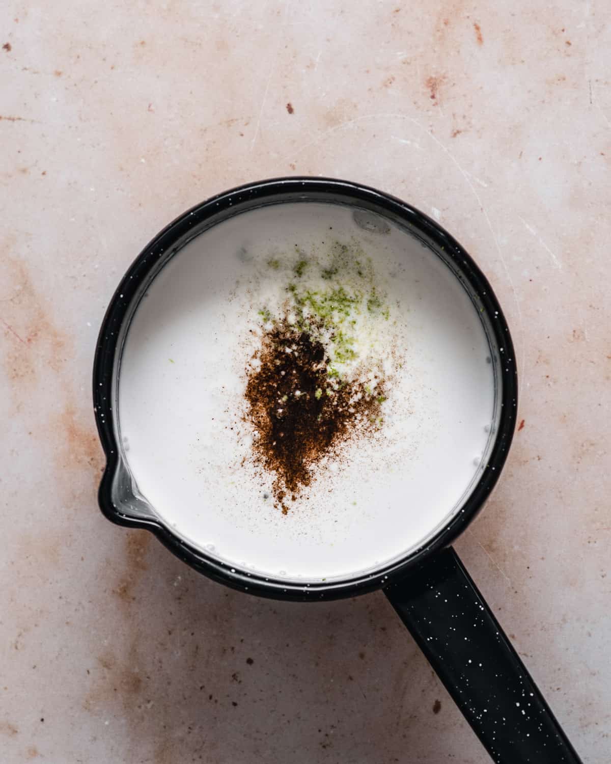 A saucepan with coconut milk, sugar, salt, vanilla and lime zest.