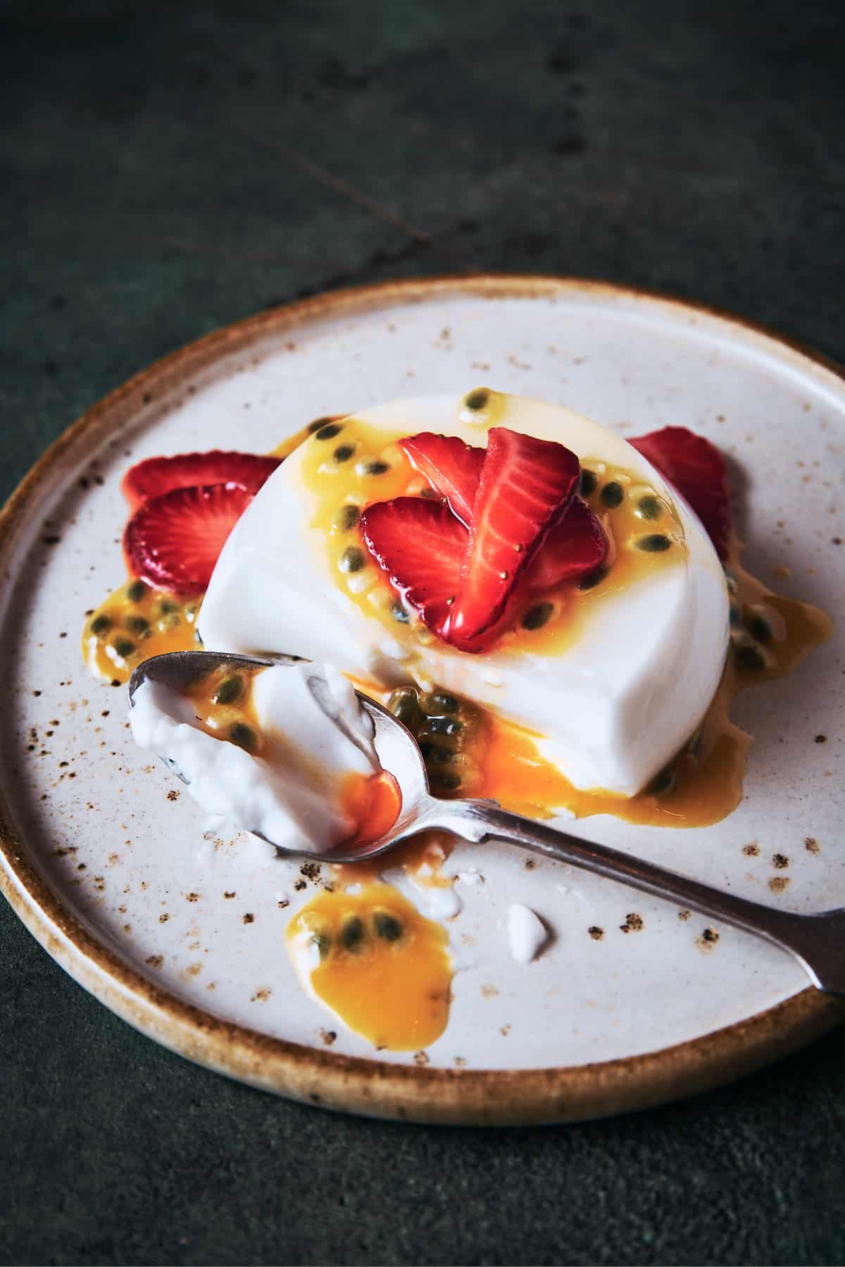 Coconut panna cotta being eaten with a spoon and showing the creamy texture inside.